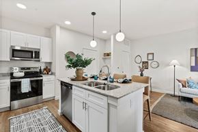 Denton apartment for rent - A modern kitchen with white cabinets and stainless steel appliances at Hudson at Pecan Creek Apartments, Texas, 76205