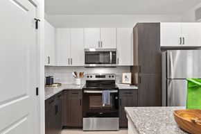 Humble apartment for rent - A modern kitchen with a stove top oven and microwave above it.