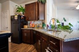 Cuero apartment for rent - A kitchen with a black refrigerator and wooden cabinets.