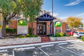 San Antonio apartment for rent - the front of a red brick building with green umbrellas