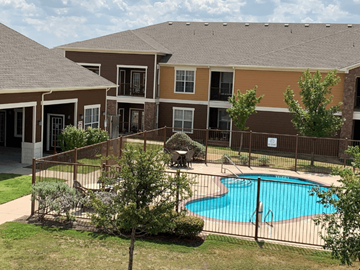 San Angelo apartment for rent - A small pool is surrounded by a fence and a building.
