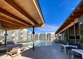 Lockhart apartment for rent - A wooden patio with chairs and a table overlooking a pool at Lockhart Farms Apartments, Lockhart, TX, 78644