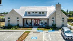 Cuero apartment for rent - A white building with a red door and a parking lot in front.
