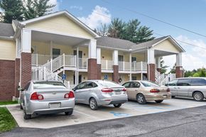 Shinnston apartment for rent - A parking lot with cars and a building in the background.