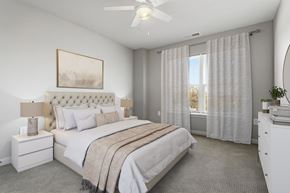 Silver Spring apartment for rent - A bedroom with a large bed, a ceiling fan, and a window with curtains.