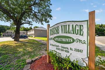 Emporia apartment for rent - A sign for Reese Village Apartments stands in front of a tree and apartment buildings.