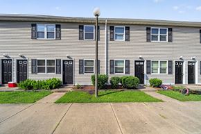 Emporia apartment for rent - A building with grey siding and black doors with windows in between.