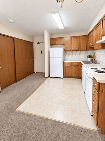 Parsons apartment for rent - A kitchen with a white refrigerator and wooden cabinets.