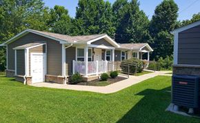 Dawson Springs apartment for rent - a small gray house with a porch and a yard with a lawn and trees