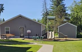 Iron River apartment for rent - A playground with a slide, swings, and a picnic table is located in front of a building.