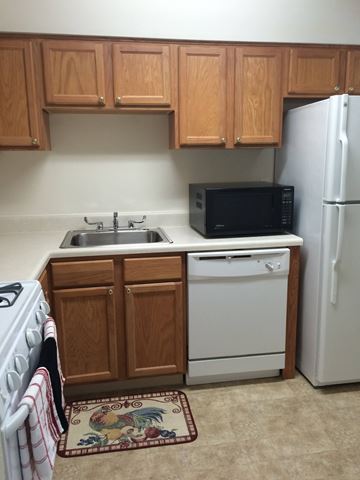 Martinsburg apartment for rent - A kitchen with a white refrigerator, a black microwave, a white dishwasher, and a white stove.