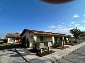 Haines City apartment for rent - A house with a red door and a green door is surrounded by plants and a sidewalk.
