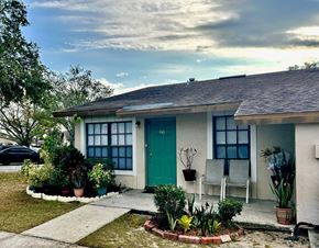 Haines City apartment for rent - A house with a green door and a white chair in front of it.