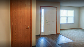 Dunkirk apartment for rent - an empty living room with a white door and wood floors