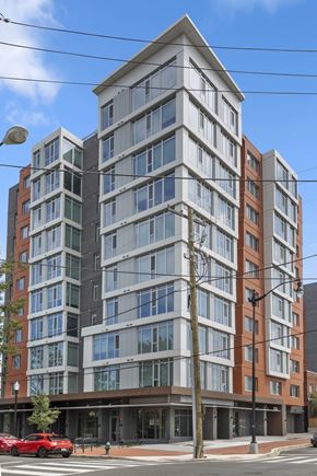 Washington apartment for rent - A modern multi-story building with a red car parked in front.