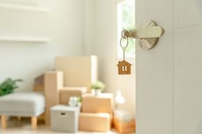 Sistersville apartment for rent - A key hanging from a door handle with boxes and a plant in the background.