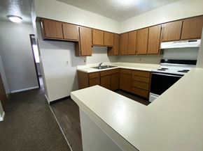 Maroa apartment for rent - an empty kitchen with white countertops and wooden cabinets