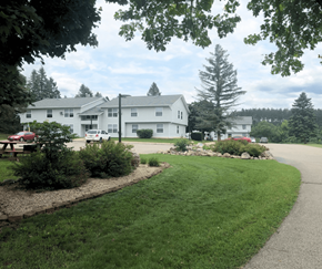 Cadillac apartment for rent - the view of a large white building with a driveway and a lawn