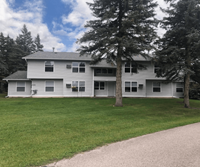Cadillac apartment for rent - a large white house with trees in front of it