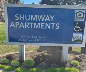 Taylorville apartment for rent - a blue sign that says in front of a yard with plants