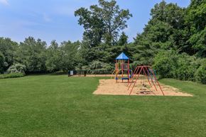Manchester apartment for rent - A playground with a blue and red swing set in the middle of a grassy area.