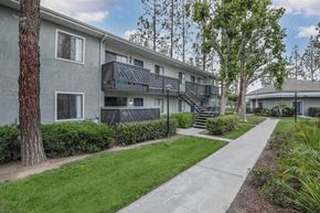 San Bernardino apartment for rent - A concrete pathway leads to a building with a balcony.