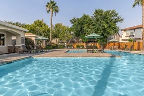 Clovis townhouse for rent - A swimming pool surrounded by palm trees and a building.