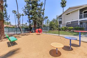 Redlands apartment for rent - A playground with a red slide, green bench, and a yellow and blue table.