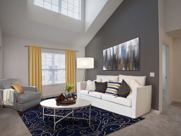 West Long Branch apartment for rent - A living room with a white couch, a grey armchair, a white coffee table, and a large abstract painting on the wall.