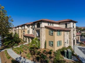Simi Valley apartment for rent - A building with a red tile roof and beige walls with green shutters.