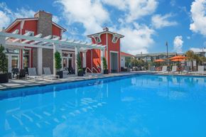 Santa Maria apartment for rent - A large swimming pool in front of a red and white building.