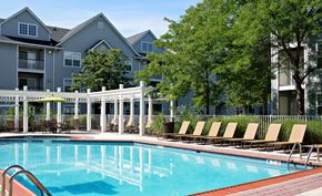 Lawrenceville apartment for rent - A pool surrounded by chairs and trees in front of apartment buildings.
