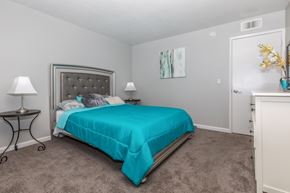 Visalia apartment for rent - A bedroom with a bed, nightstand, and lamp.