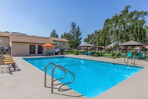 Visalia apartment for rent - A swimming pool with a blue water and a sun umbrella.