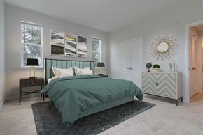 Oxnard apartment for rent - A bedroom with a bed, nightstand, and a wall hanging.