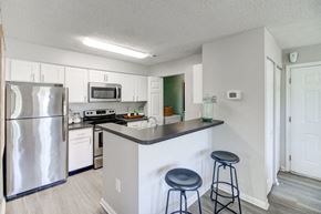 Lawrenceville apartment for rent - A kitchen with a refrigerator, microwave, oven, and a counter with two stools.