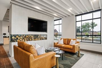 South Bend apartment for rent - A living room with a tan couch and a flat screen TV mounted on the wall.