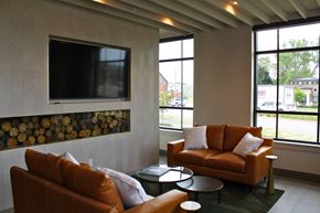 South Bend apartment for rent - A living room with a brown couch and a television mounted on the wall.