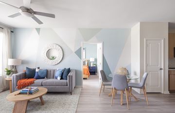 Wesley Chapel apartment for rent - A living room with a grey sofa, a round table, a ceiling fan, and a dining table with chairs.