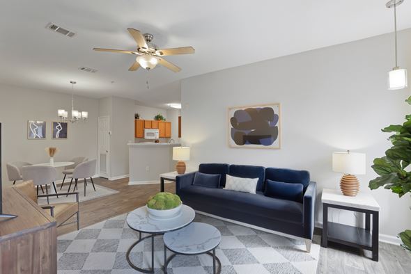 Pensacola apartment for rent - A living room with a blue couch and a table with a plant on it.