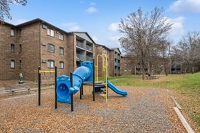Eden Prairie apartment for rent - A playground with a blue slide and yellow railing in front of a brick building.