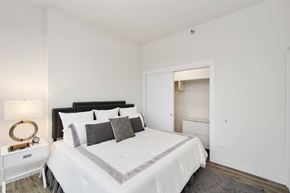 Chicago apartment for rent - A bedroom with a large bed and a nightstand with a lamp.