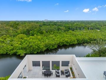 Miami apartment for rent - A balcony overlooks a lush green forest and a body of water.