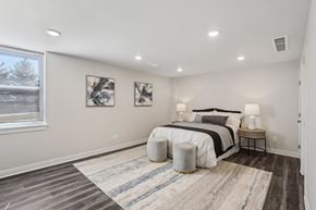 Blue Springs apartment for rent - Blue Springs, MO Townhomes - Chapman Ridge Townhomes - A Bedroom With Queen-Sized Bed, Abstract Wall Art, Vinyl Plank Flooring, Matching Bedside Lamps, And A Large Window.