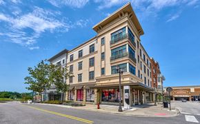 Kansas City apartment for rent - A street view of a multi-story building with a clear blue sky above.