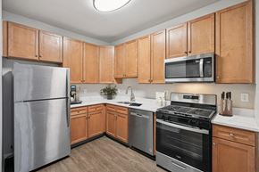 Cherry Hill apartment for rent - Three-Bedroom Garden-Style Apartments in Cherry Hill, NJ - The Highlands at Cherry Hill - Kitchen With White Counters, Wood Cabinets, Stainless Steel Appliances, and Ceiling Light.
