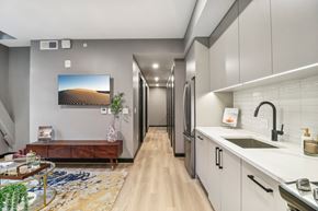 Washington apartment for rent - a kitchen with gray cabinets and a long hallway with a tv on the wall