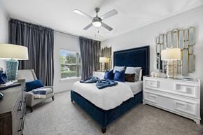 Fort Worth apartment for rent - A bedroom with a large bed, a ceiling fan, and a window with curtains.