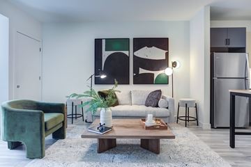 Des Plaines apartment for rent - A living room with a green chair, a white couch, and a painting on the wall.