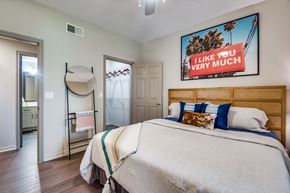 Houston apartment for rent - A bedroom with a large bed and a picture of palm trees on the wall.